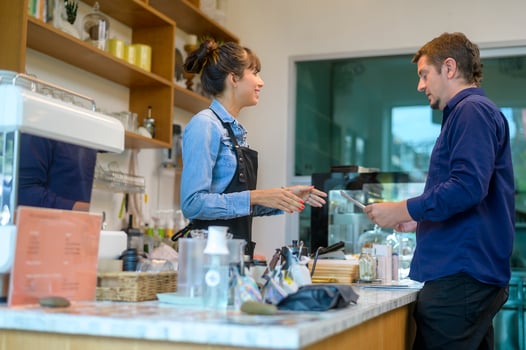 Young service minded barista woman with customer in coffee shop photo