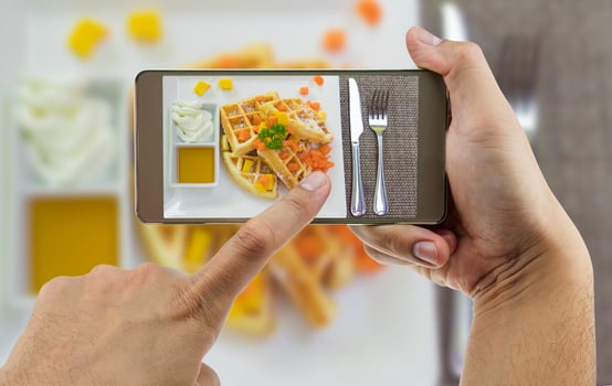 People using mobile phone taking photo of colorful waffles on white plate