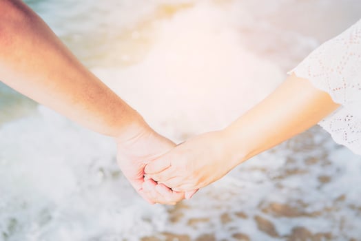 Asian couple is holding hand near to the sea with warm sun light sky photo