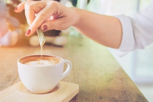 Closeup of lady pouring sugar while preparing hot coffee cup photo