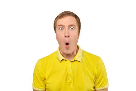 Surprised young man with funny facial expression in yellow T-shirt, white isolated background photo