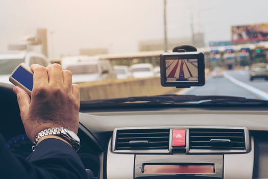 Man driving car using navigator and holding electronic toll collection system device photo