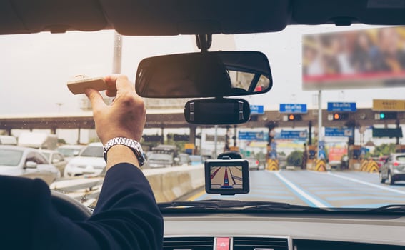 Man driving car using navigator and holding electronic toll collection system device photo