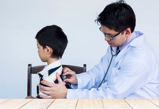 Sick asian boy being examined by male doctor over white background photo