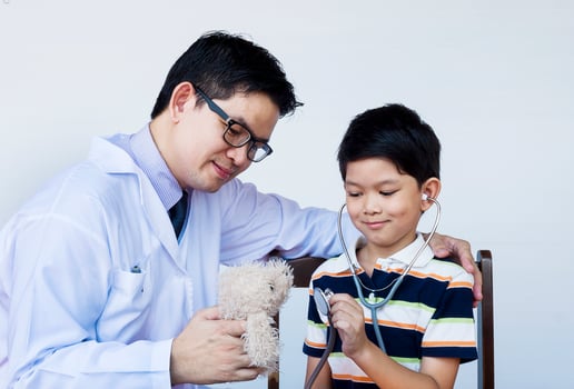 Asian boy and doctor during examining using stethoscope over white background photo