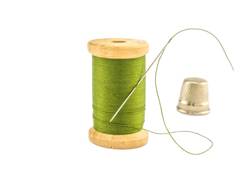 Isolated wooden spool of green thread with a needle photo
