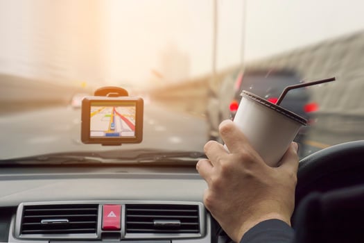 Man driving car using navigator and holding coffee cup photo