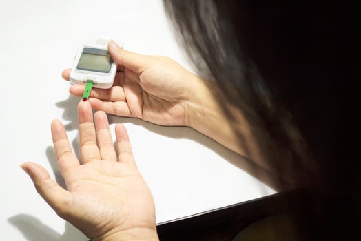 Woman is checking diabetes using blood checking kit isolated over white photo