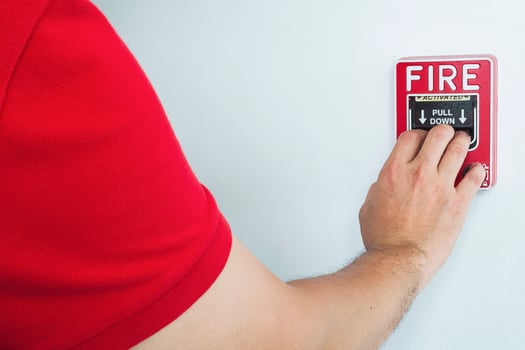 Man is reaching his hand to push fire alarm hand station photo