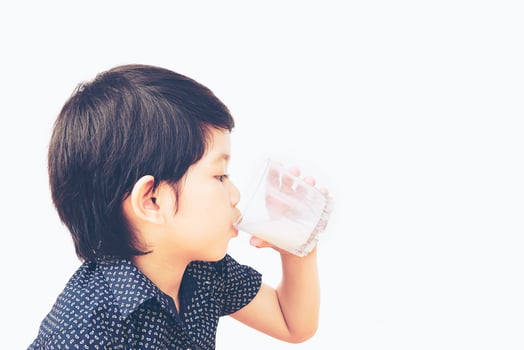 Vintage style photo of Asian boy is drinking a glass of milk
