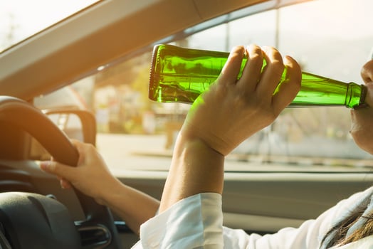 Woman drinking beer while driving a car photo