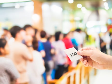 Male hand holding queue card over long line waiting people photo