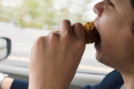 Business man driving car while eating fried chicken dangerously photo