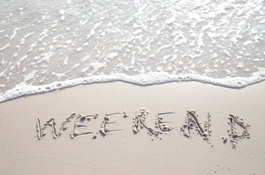 Word WEEKEND hand written in the sand. Close up sand texture on beach in summer. Vacation, holiday concept, photo