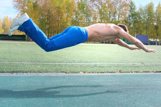middle aged man doing jumping push-ups on a stadium. photo