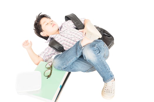 Tired eight years boy sleeping his school belonging isolated over white photo