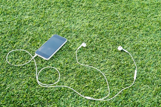 Mobile phone with head phone on green artificial grass photo