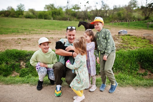Father with four kids on an animal eco farm hold baby sheep lamb in hand. photo