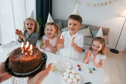 Woman holding cake with candles. Celebrating birthday. Group of children is together at home at daytime photo
