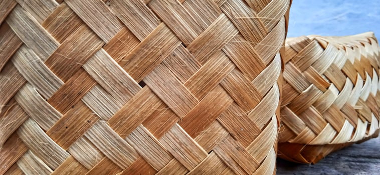 Yellow brown bamboo woven box on the gray background. A traditional green box packaging used for food or food ingredients. Green packaging. photo