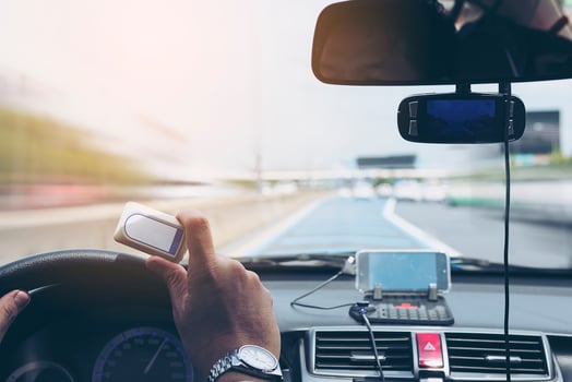 Man driving car using navigator and holding electronic toll collection system device photo