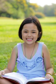 Asian little girl reading book in the park photo