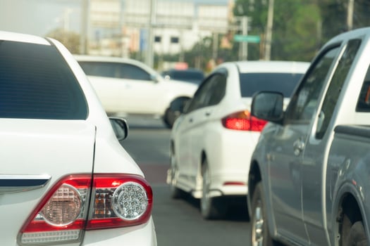 Rear side of white car driving or stop on the asphalt road. wtih other cars to beside. blurred of cars drive through the front of the junction in the city. photo