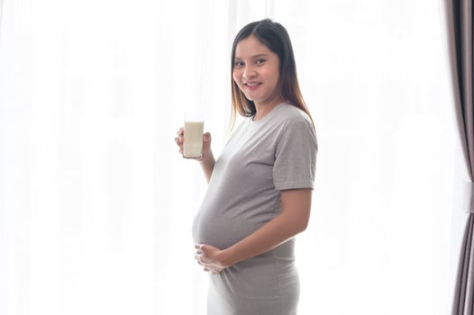 Young pregnant woman drinking milk at home, healthcare and pregnancy care photo