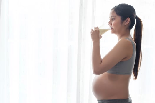 Young pregnant woman drinking milk at home, healthcare and pregnancy care photo