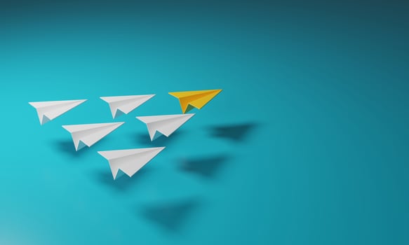 Yellow paper airplane leads a group of white planes. photo