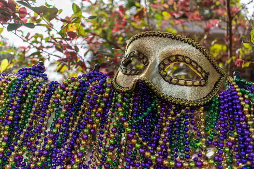 Mardi Gras beads covering wrought iron fence with carnival mask photo