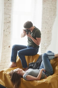 Photographer taking a shot of young girl that lying on the white sofa photo