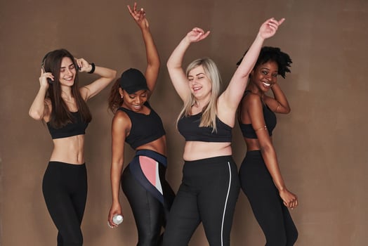 Let's get party started. Group of multi ethnic women standing in the studio against brown background photo