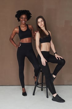 Close friends. Two multi ethnic female stands in the studio with brown background photo