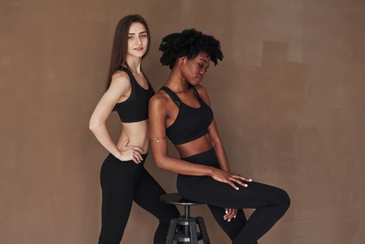Stunning cute women.Two multi ethnic female friends stands in the studio with brown background photo