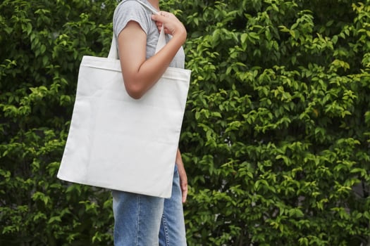 hipster woman with white cotton bag on green leaf background photo