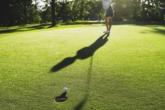 golf player putting golf ball into hole photo