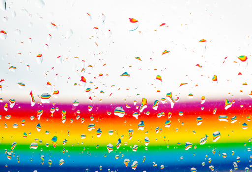 A rainbow behind a glass windows with water drops, Point of view, from behind the glass with drops. photo