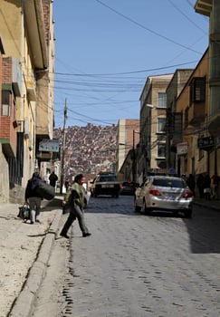 La Paz, Bolivia - June 2, 2018 - People crossing the steep streets of La Paz, Bolivia, with more red brick houses in the background. photo