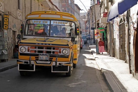 La Paz, Bolivia, 2018 - A bus works its way through the narrow streets of La Paz, Bolivia, on a sunny day. photo