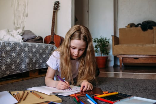 The girl after school plays at home, draws with pencils and felt-tip pens photo