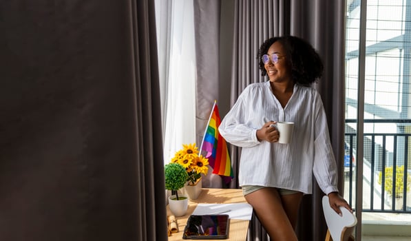 African American girl with LGBTQ rainbow flag in her bed room for coming out of the closet and pride month celebration to promote sexual diversity and equality in homosexual orientation concept photo