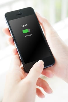 Female hand holding mobile phone with charged battery on screen photo
