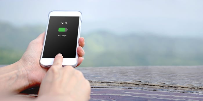Female hand holding mobile phone with charged battery on screen photo