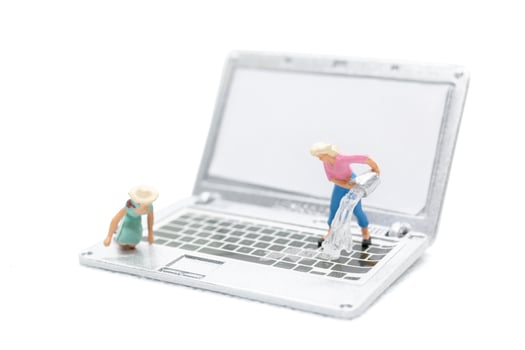 Miniature people cleaning laptop computer on white background photo