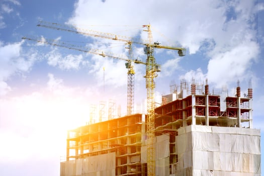 Hoisting cranes working building construction on bright blue sky and big cloud with sun flare background. photo