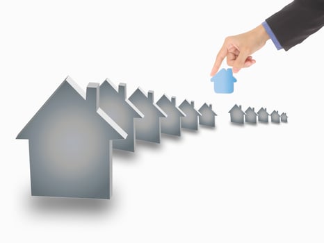 Hand picking up a small house, isolated on a white background photo