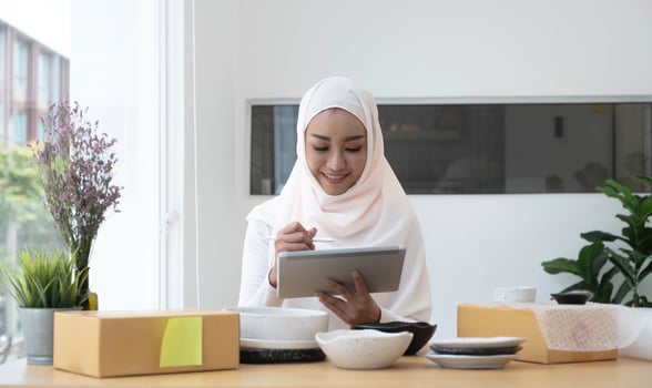 Attractive muslim female entrepreneur, e-commerce business owner packing preparing a shipping box in her office. photo