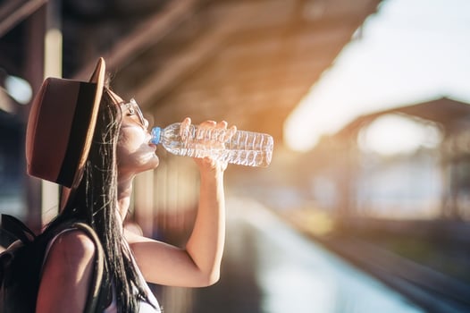 Young woman back pack traveler drink fresh water in train station - outdoor asian traveler activity concept photo