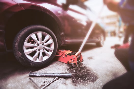 Car tire changed for maintenance in garage using hydraulic jack - car maintenance concept photo